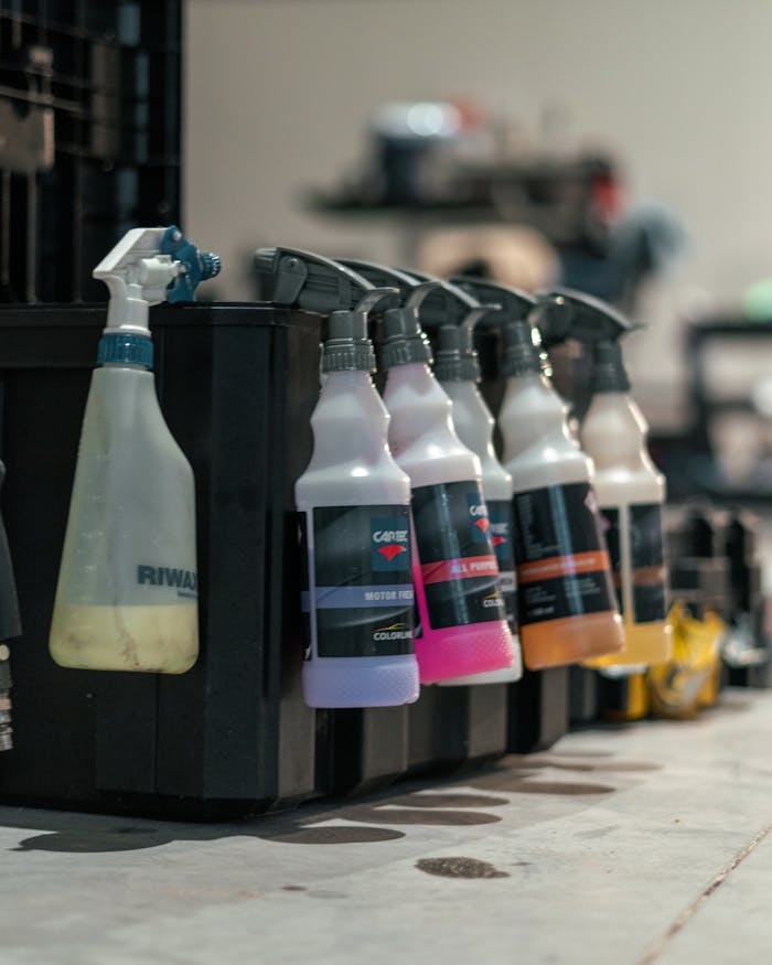Close-up of various car care spray bottles lined up in a workshop.